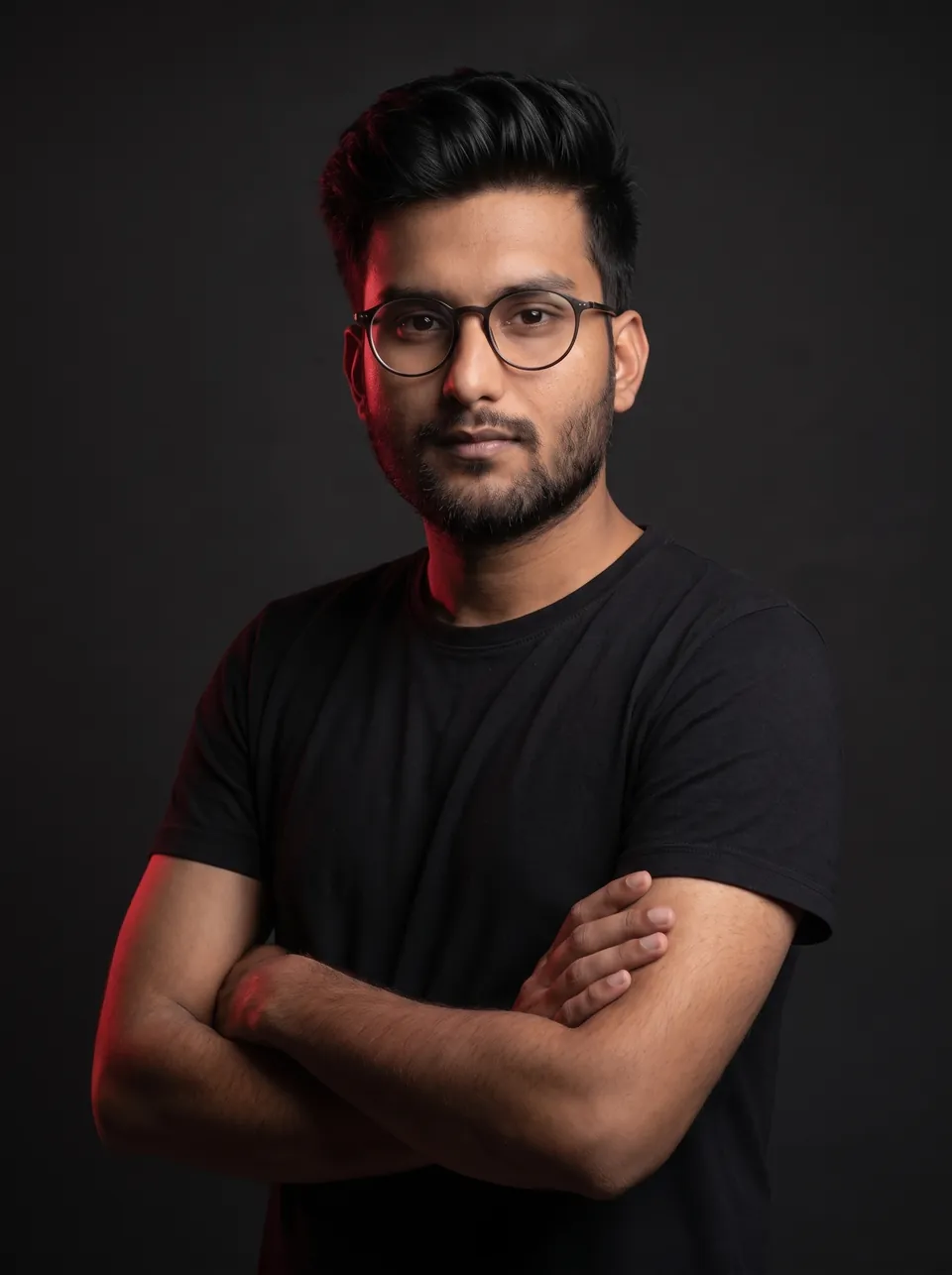 Portrait of Anurag Jha in a black t-shirt, arms crossed, against a dark studio background.